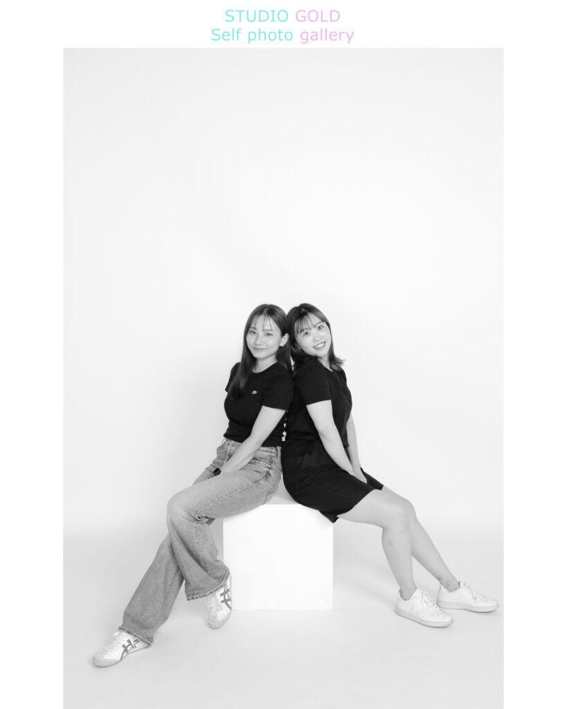 セルフ写真館でリモコンを使いながら楽しそうにポーズをとる友達2人。神戸三宮スタジオゴールドの広々とした撮影空間