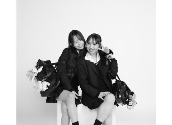 神戸三宮セルフ写真館スタジオゴールドで制服姿の友達同士が仲良く座ってモノクロ撮影している様子