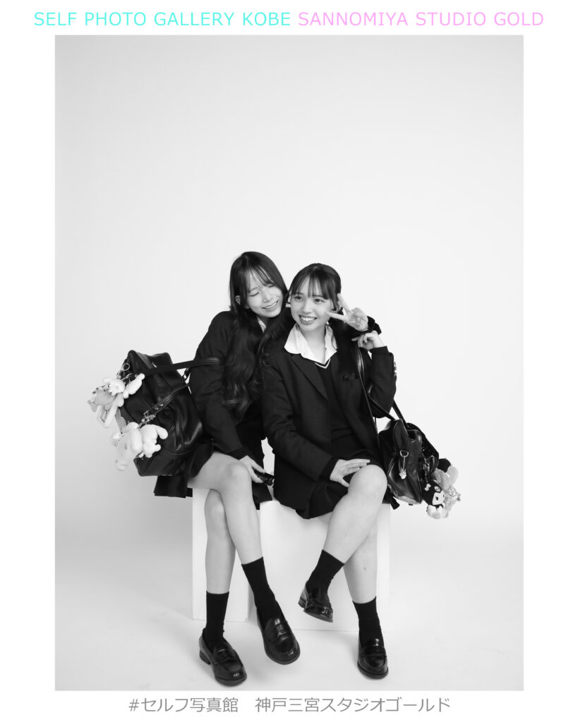 神戸三宮セルフ写真館スタジオゴールドで制服姿の友達同士が仲良く座ってモノクロ撮影している様子