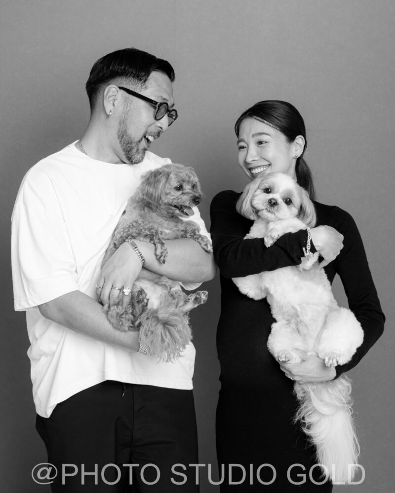 お互いに笑顔を交わしながらお腹に手を添えるご夫婦の姿。幸せな瞬間を切り取ったスタジオゴールドのマタニティ写真。